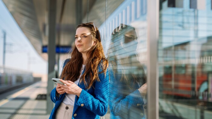 Junge Frau mit Mobilphone wartet auf ihren Zug