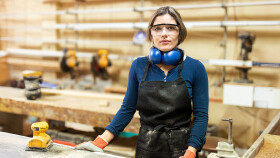 Junge Tischlerin mit Schutzbrille