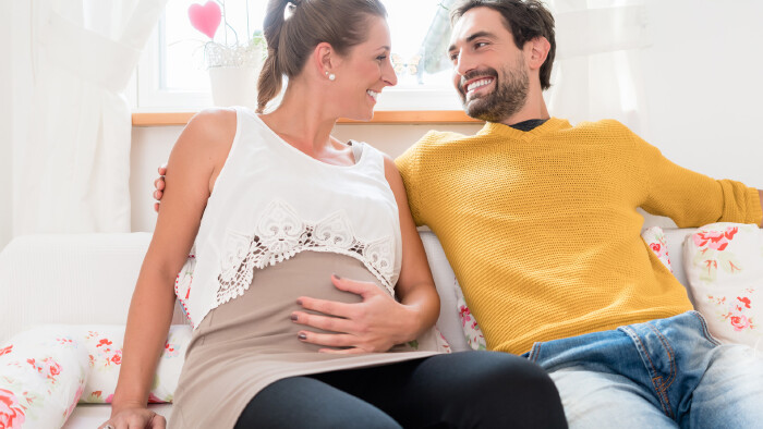 Werdende Eltern sitzen im Wohnzimmer