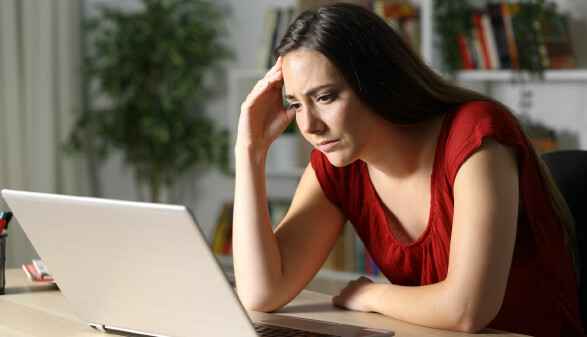 frustrierte junge Frau liest am Laptop