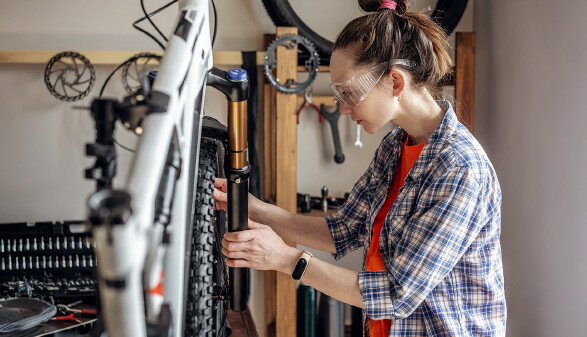 Junge Frau repariert ein Mountainbike in einer Werkstatt