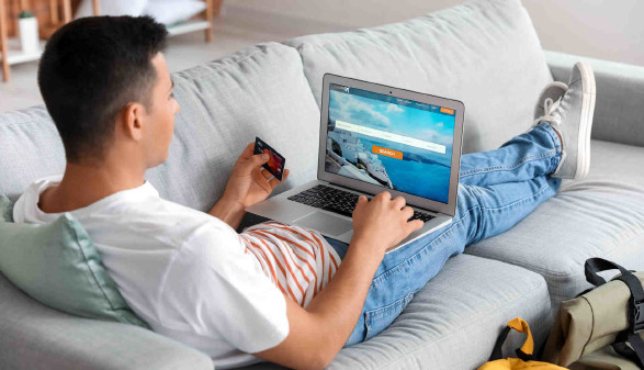 Mann auf der Couch bucht einen Flug online