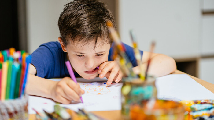 Kind mit Down Syndrom malt in der Schule