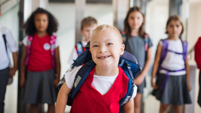 Schulkind mit Down Syndrom läuft den Flur entlang