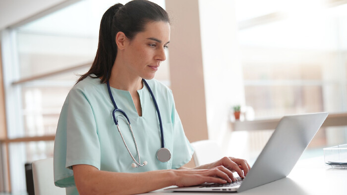 Krankenschwester schreibt am Laptop