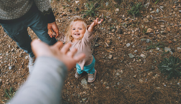 Ein kleines M&auml;dchen geht mit Vater und Mutter im Freien spazieren.