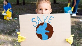  Bub h&auml;lt ein Plakat mit einer Weltkugel und der Aufschrift "Save" in die H&ouml;he