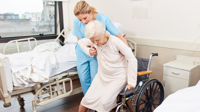 Pflegekraft hilft älteren Frau in den Rollstuhl © Robert Kneschke, stock.adobe.com