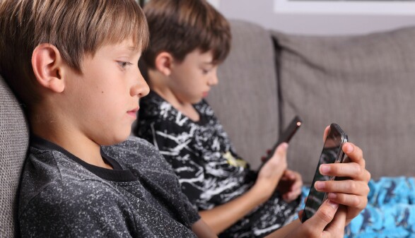 2 Buben blicken auf ihre Smartphones