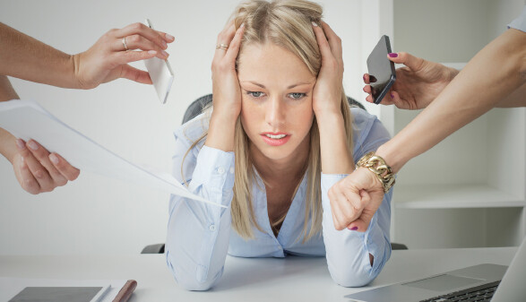 Frau sitzt am Schreibtisch und wird mit Arbeit zugesch&uuml;ttet.