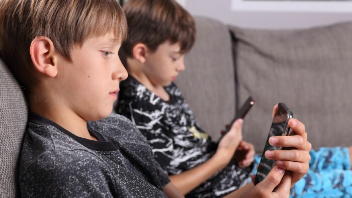 2 Buben blicken auf ihre Smartphones
