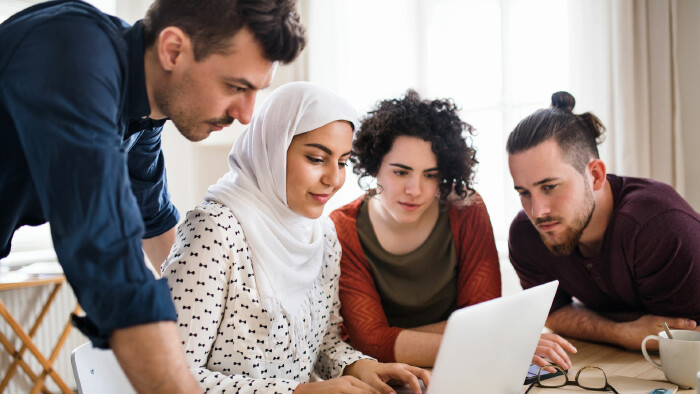 Vier Personen arbeiten gemeinsam an einem Laptop.