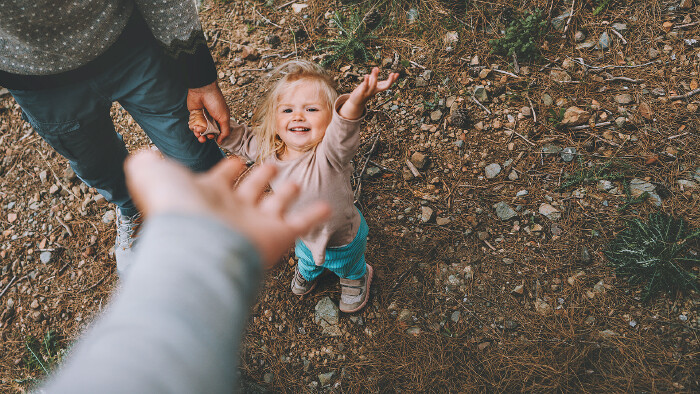 Ein kleines M&auml;dchen geht mit Vater und Mutter im Freien spazieren.
