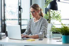 Frau arbeitet in Büro an Laptop