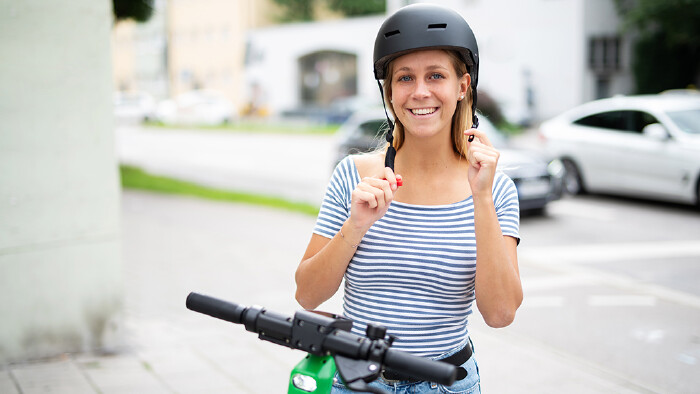 Frau setzt Helm auf.