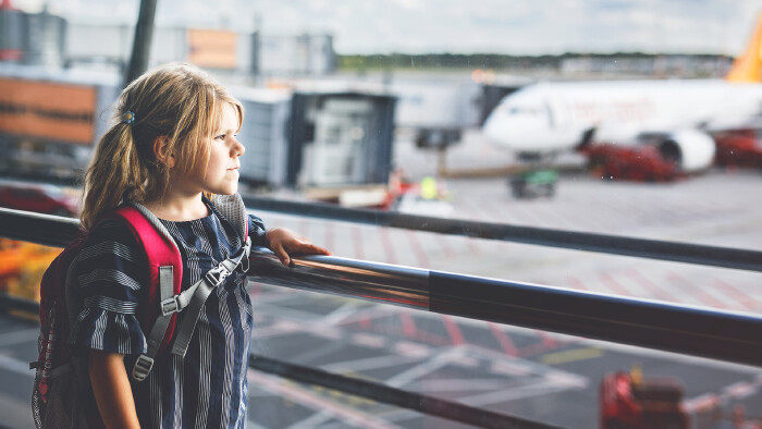 Little girl at the airport waiting for boarding at the big window. 