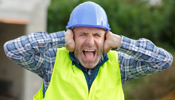 Arbeiter h&auml;lt sich wegen L&auml;rm die Ohren zu