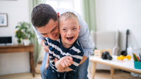 Papa spielt mit glücklichem Sohn mit Down Syndrom zu Hause