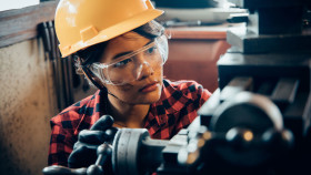 Junge Arbeitnehmerin mit Schutzhelm und -brille