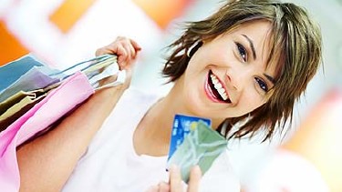 Lächelnde Frau hält mehrere Einkaufstaschen in der einen, zwei Kreditkarten in der anderen Hand. © Yuri Arcurs, Fotolia.com