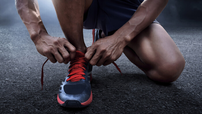 Person bindet sich die Laufschuhe zu