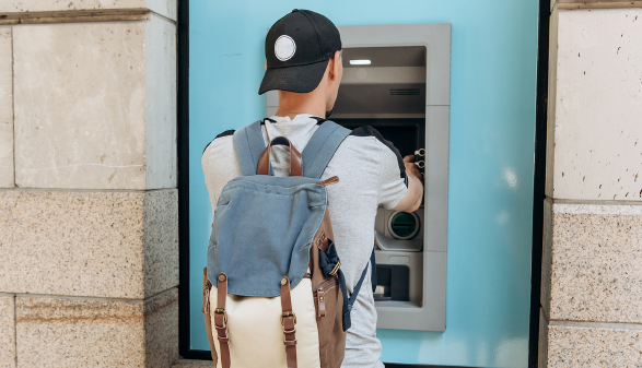 Junger Mann hebt bei Bankomat Geld ab