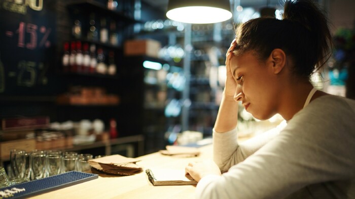 Müde Kellnerin, die am Ende des Arbeitstages Notizen zu Bestellungen und Trinkgeldern liest